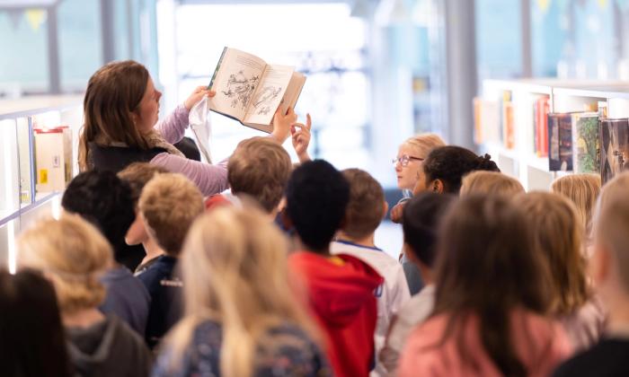 Ansatt viser bok til en klasse på besøk på Sølvberget.