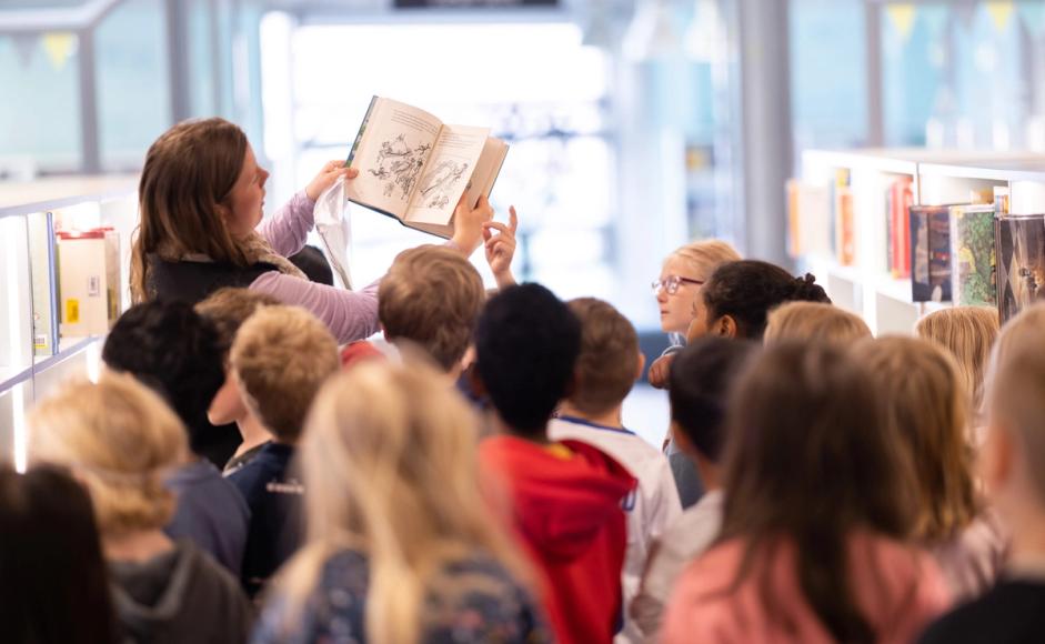Ansatt viser bok til en klasse på besøk på Sølvberget.