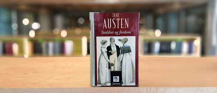 Stolthet og fordom av Jane Austen stående på bokhylle i biblioteket