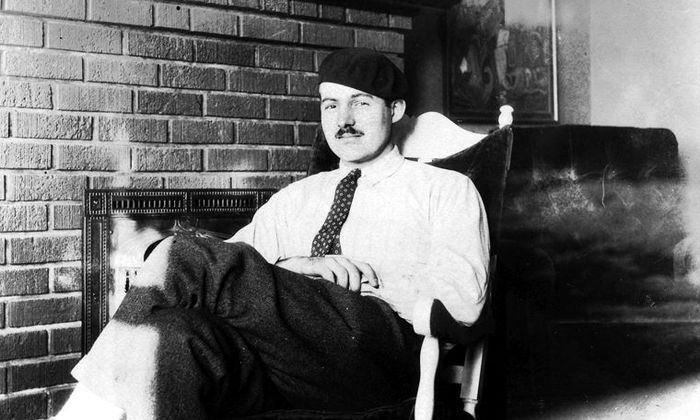 Ernest Hemingway sittende i en stol med lue på