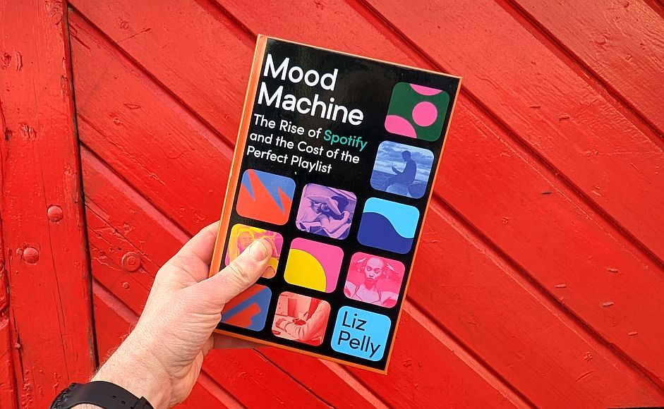 Boka Mood machine av Liz Pelly holdt foran en rød vegg