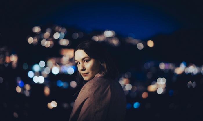 Portrett av Unnveig Aas med mørk bakgrunn utendørs