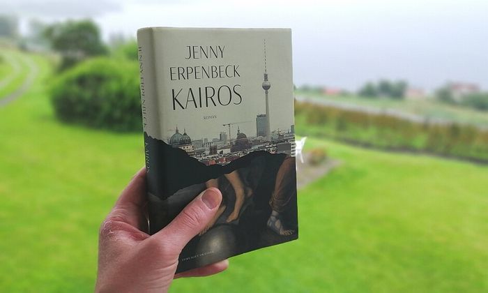 Kairos av Jenny Erpenbeck holdt foran en hage i grått vær