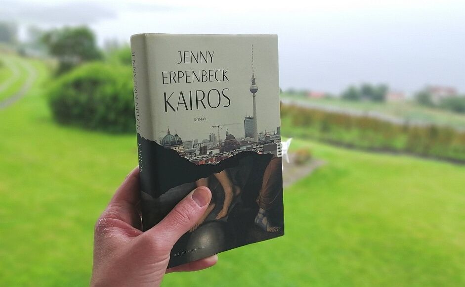 Kairos av Jenny Erpenbeck holdt foran en hage i grått vær