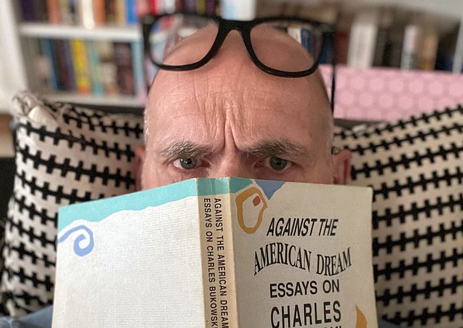 Tom H. Brekke med bok foran ansiktet.