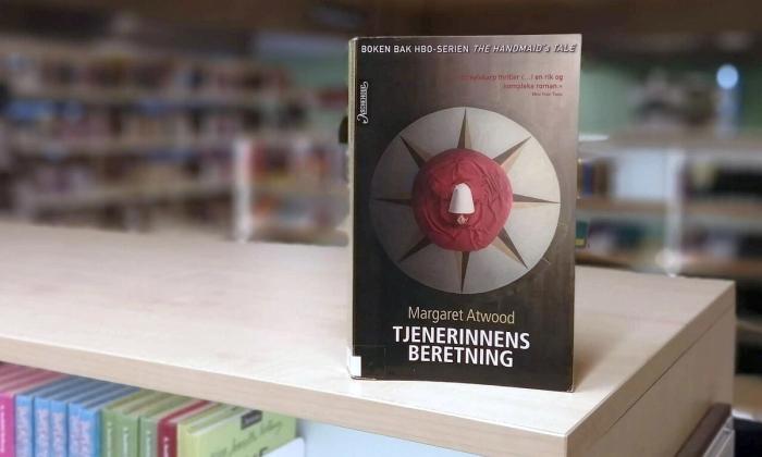 Tjenerinnens beretning av Margaret Atwood bok stående på bokhylle i bibliotek