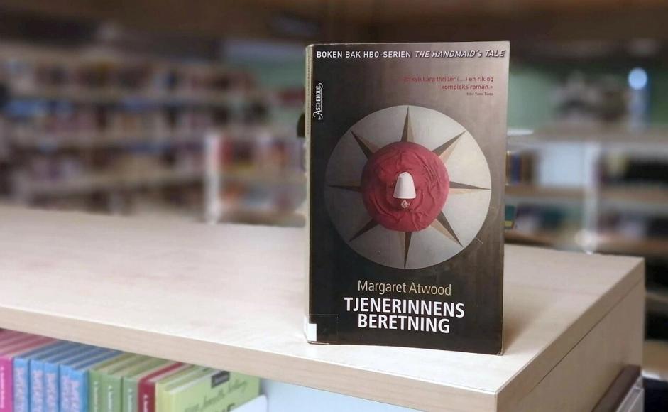Tjenerinnens beretning av Margaret Atwood bok stående på bokhylle i bibliotek