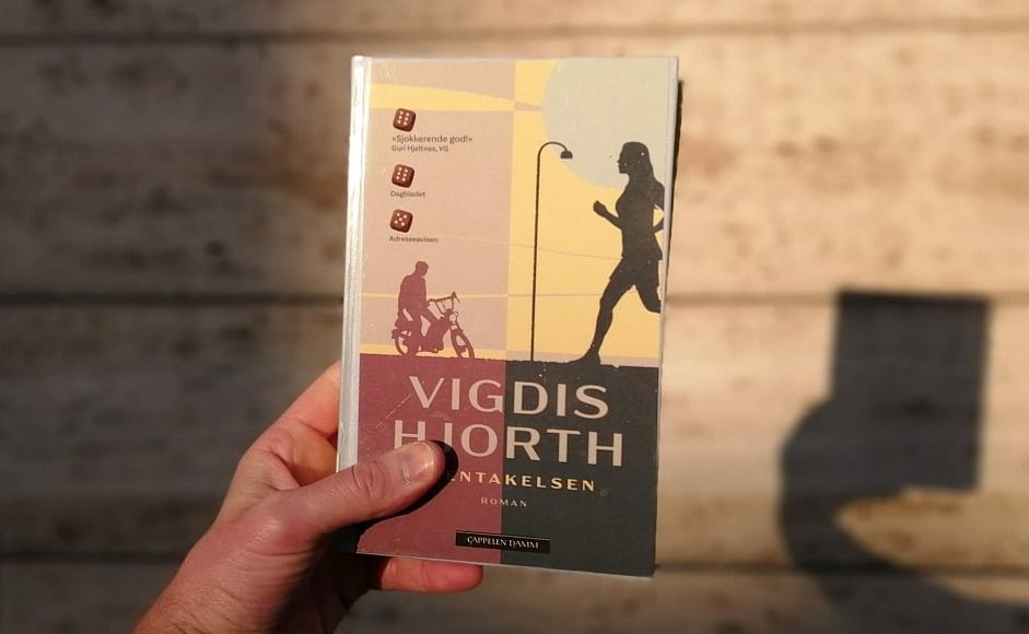 Boka Gjentakelsen holdt foran en vegg i sollys