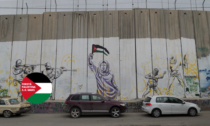 Foto av en mur med veggmaleri i Palestina med piggtrå på toppen.