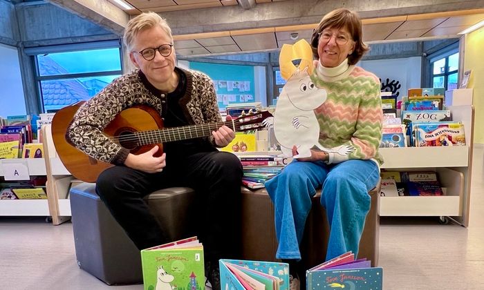 Foto av Ebbe Helberg og Eli Gunn Buvik som viser bøker og mumitrollet med bursdagskrone