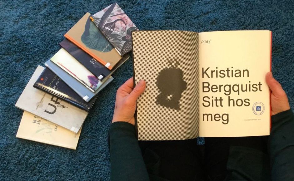 Person som leser i bok av Kristian Bergquist med bøker på gulvet ved siden av