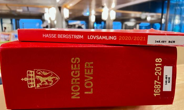 Norges lover og lovsamling liggende på en bokhylle