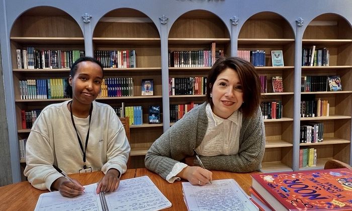 Foto av to kvinnelige ansatte som skriver tekster i biblioteket.