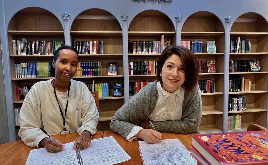 Foto av to kvinnelige ansatte som skriver tekster i biblioteket.