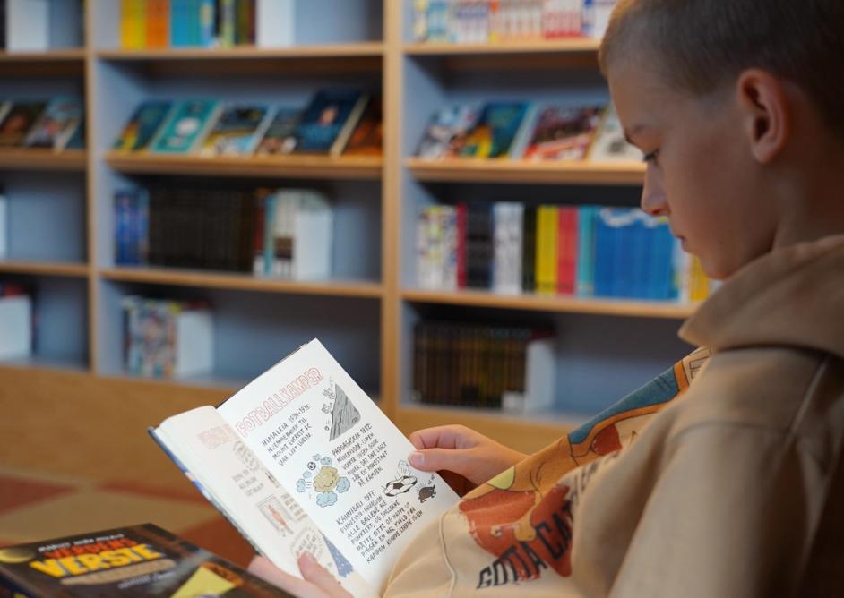 Gutt leser bok på biblioteket