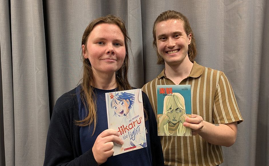 Einar Hildonen og Mette Henriksen holder mangabøker foran grå gardin