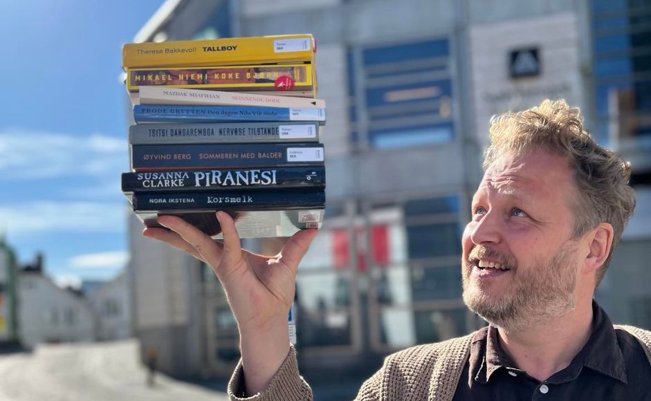 Tomas Gustafsson holder opp de nominerte bøkene bibliotekets litteraturpris 2024. 