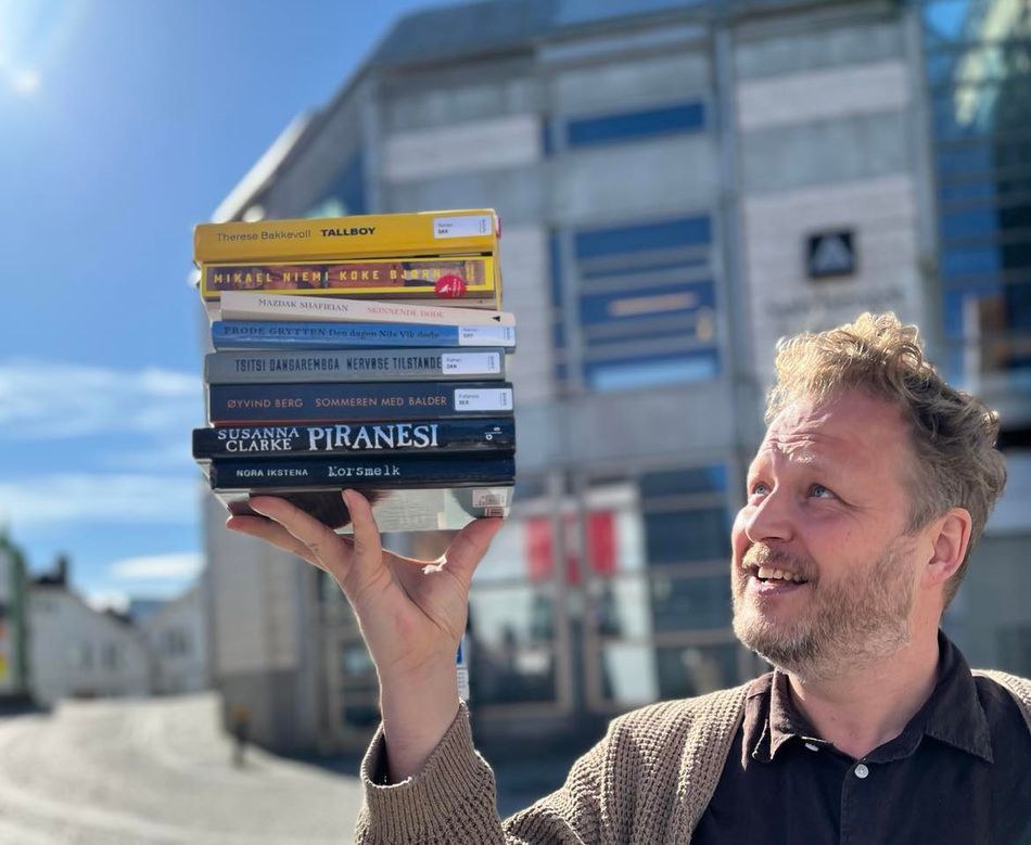 Tomas Gustafsson holder opp de nominerte bøkene til Bibliotekets litteraturpris 2024.