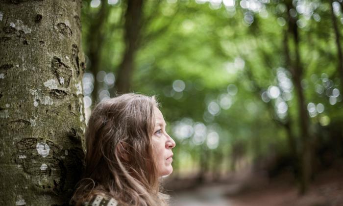 Gunhild Seim stående ved et tre