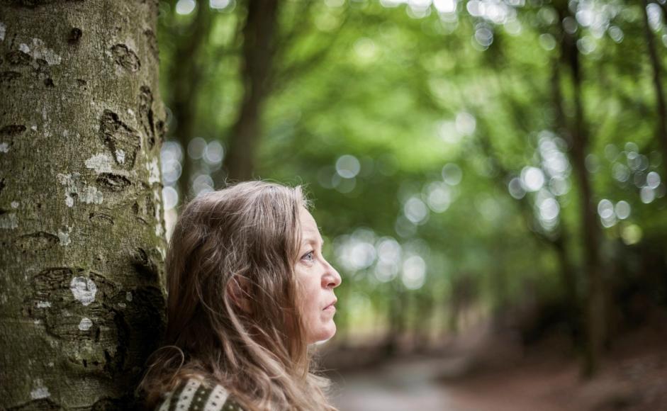 Gunhild Seim stående ved et tre