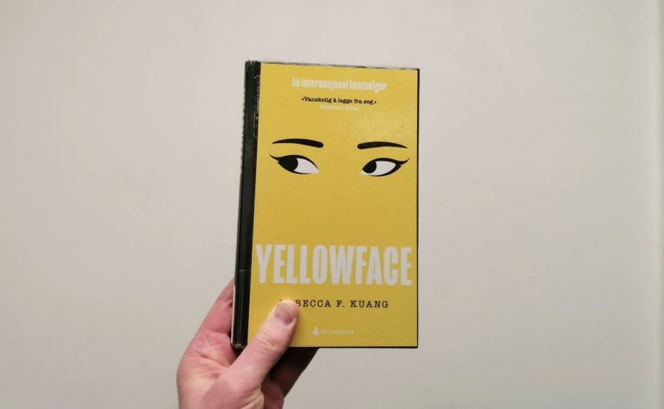 Boka Yellowface av Rebecca F. Kuang holdt foran en hvit vegg