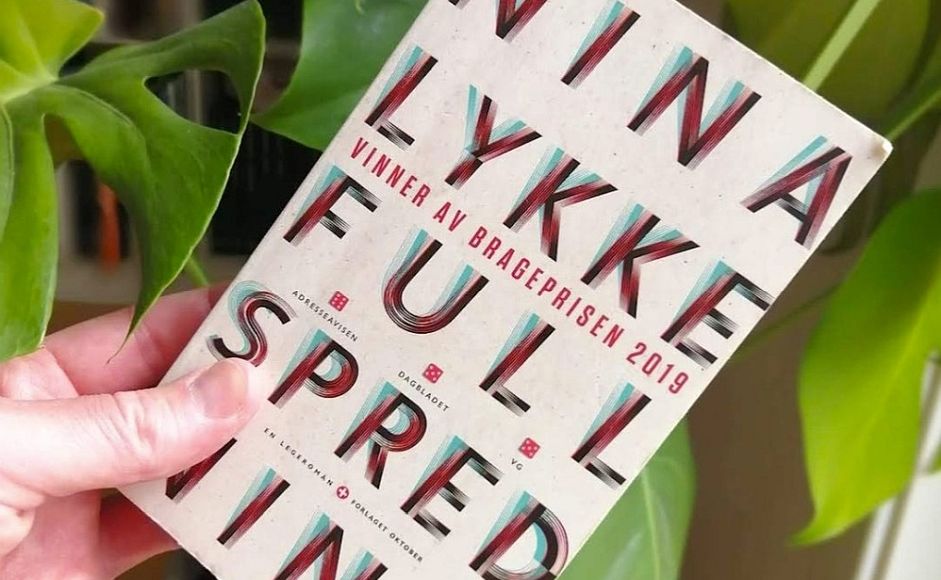 Full spredning av Nina Lykke holdt foran en grønn plante