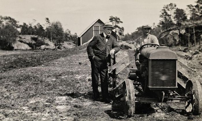 Knut Hamsun stående ved siden av traktor