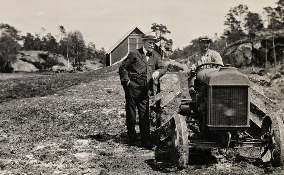 Knut Hamsun stående ved siden av traktor