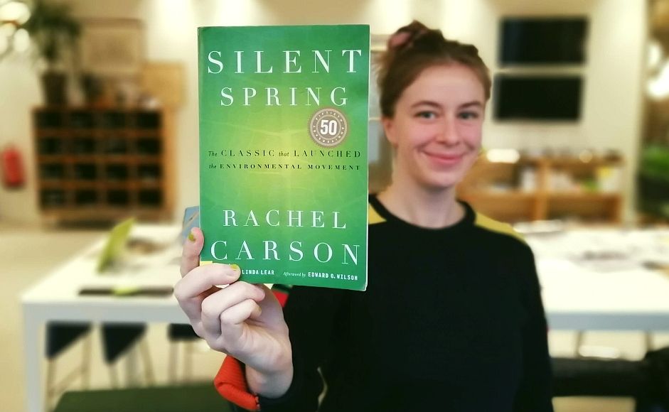 Hannah Ersland holder boka Silent Spring av Rachel Carson mot kameraet i kontorlandskap