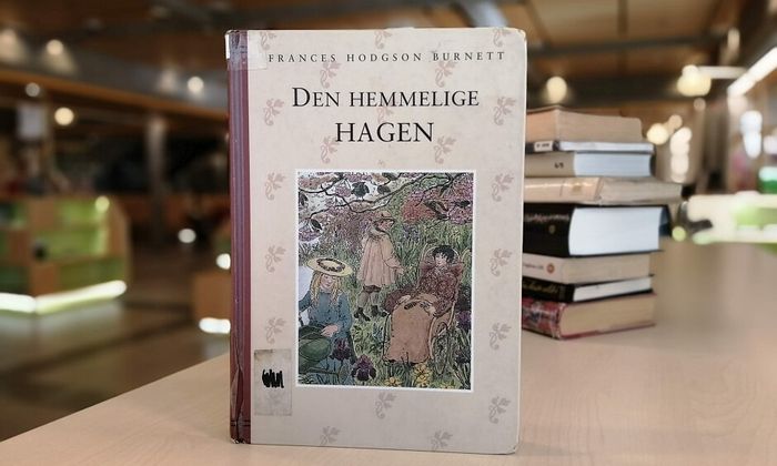 Den hemmelige hagen av Frances Hodgson Burnett stående på hylla i biblioteket