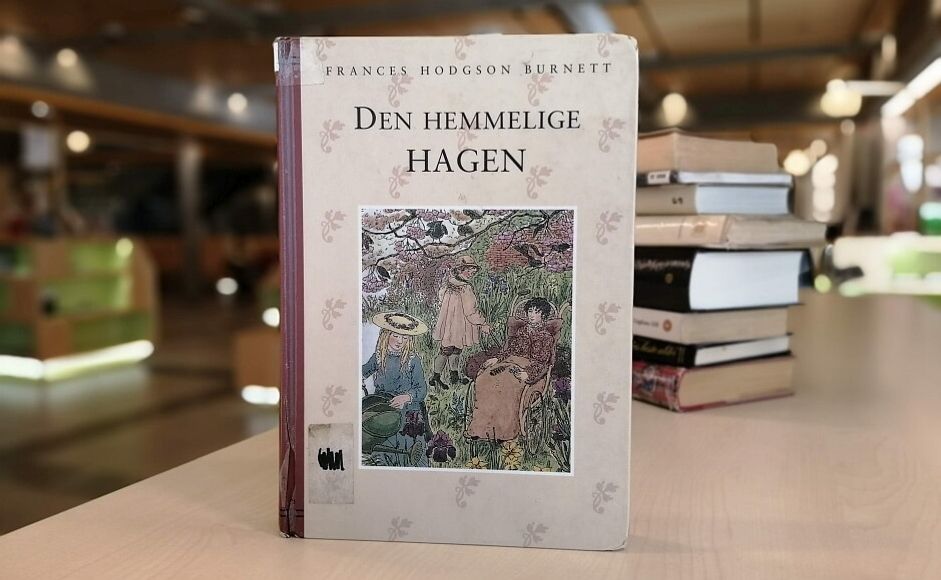 Den hemmelige hagen av Frances Hodgson Burnett stående på hylla i biblioteket