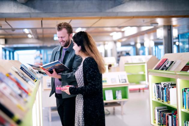 Christian Tønnessen hjelper en låner i biblioteket