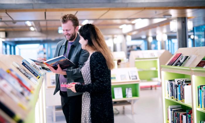 Christian Tønnessen hjelper en låner i biblioteket