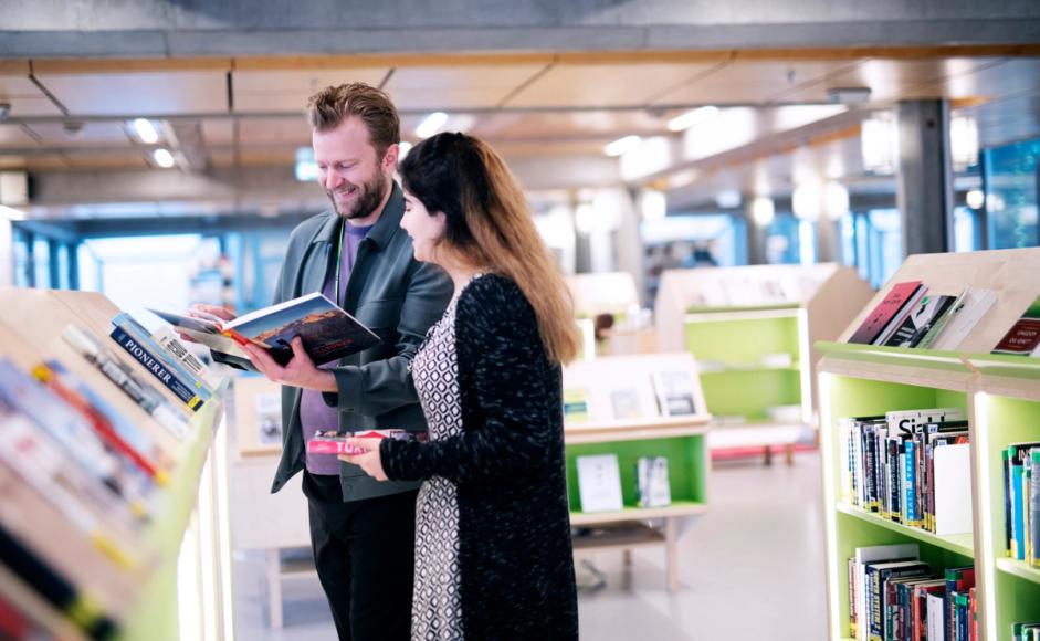 Christian Tønnessen hjelper en låner i biblioteket