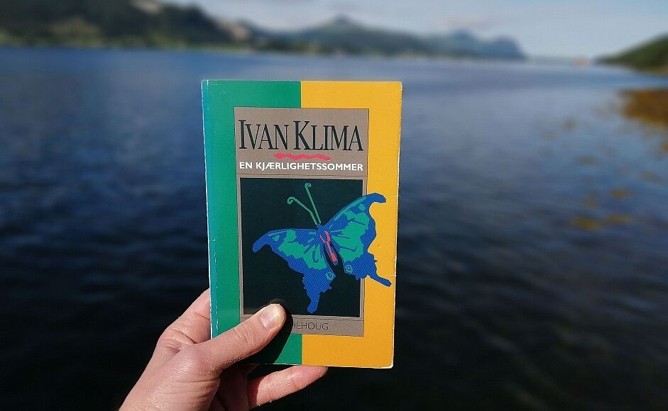 Boka En kjærlighetssommer av Ivan Klíma holdt foran en fjord