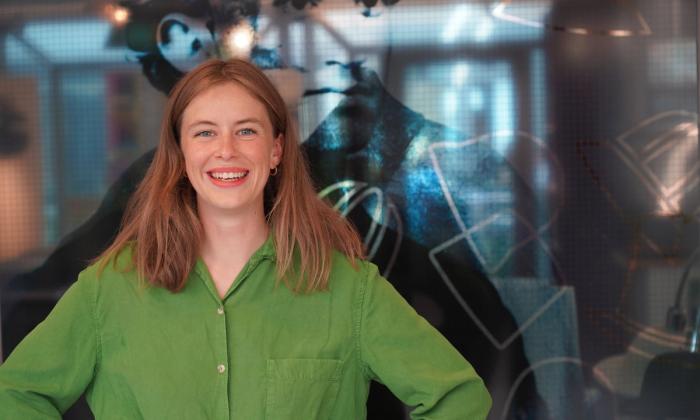 Ny leder for Kiellandsenteret, Hannah Ersland, smiler foran inngang til Kiellandsenteret i 4. etasje