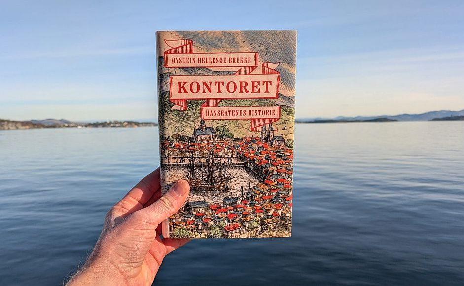 Boka Kontoret av Øystein Hellesøe Brekke holdt foran en stille fjord