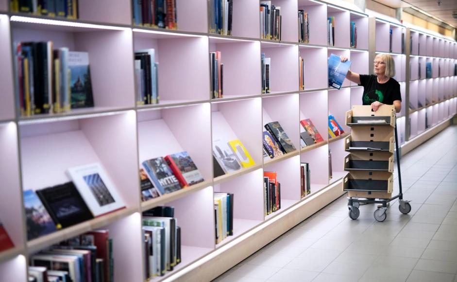 En bibliotekar rydder på plass bøker
