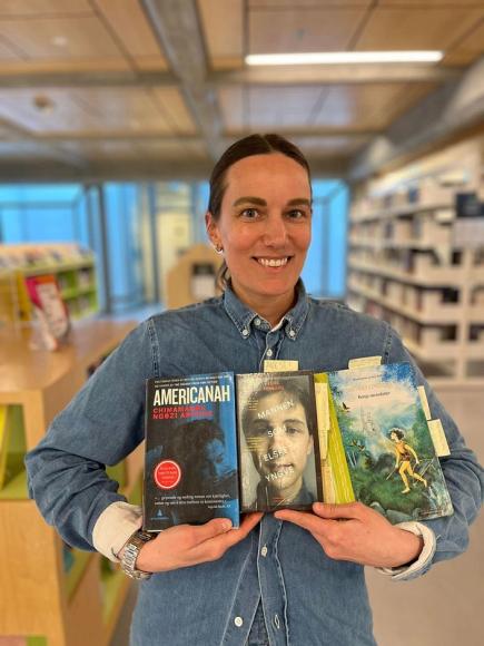 Lene Jakobsen holder sine bøker Americanah, Mannen som elsket Yngve og Ronja Røverdatter. Foto: Nana Thejll Jakobsen/Sølvberget.