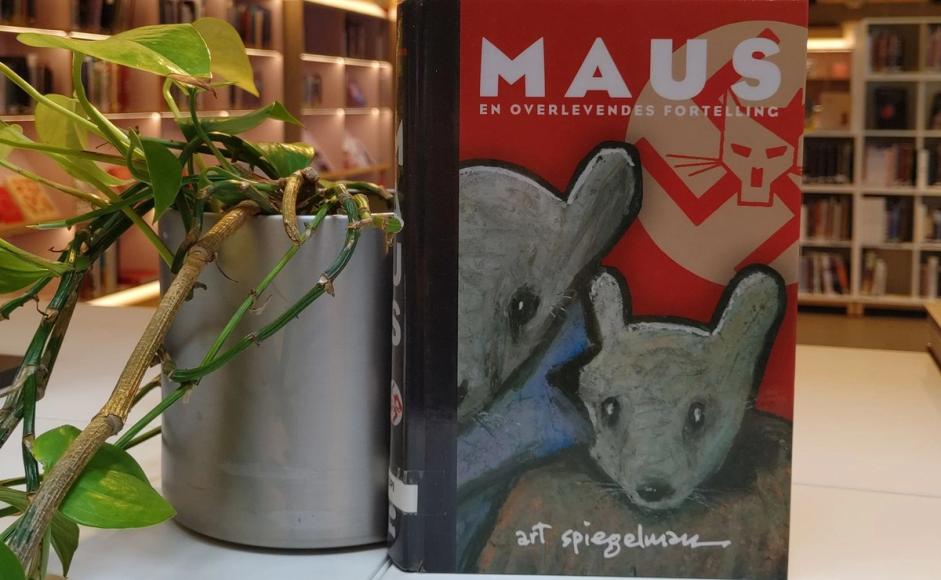 Bilde av boka Maus ved siden av en plante. I bibliotekmiljø.