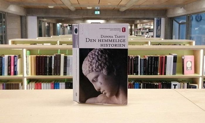 Den hemmelige historien av Donna Tartt stående på hylle i bibliotek