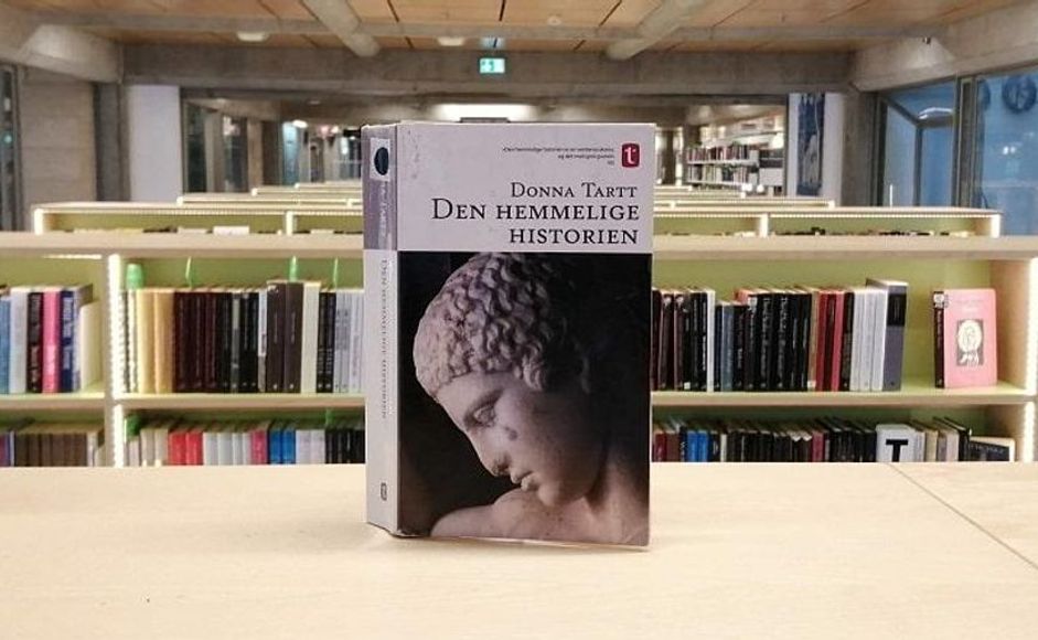 Den hemmelige historien av Donna Tartt stående på hylle i bibliotek