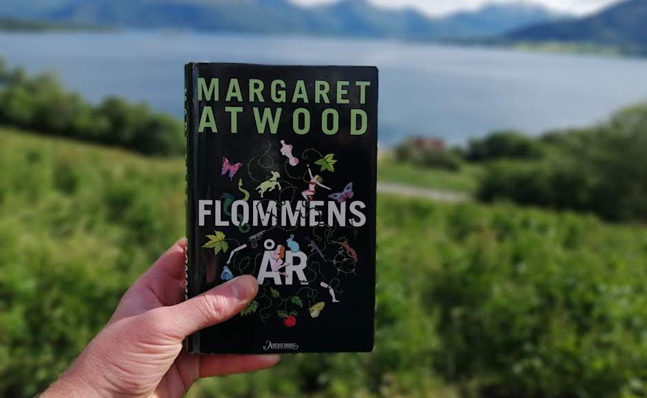 Flommens år av Margaret Atwood holdt foran en fjord