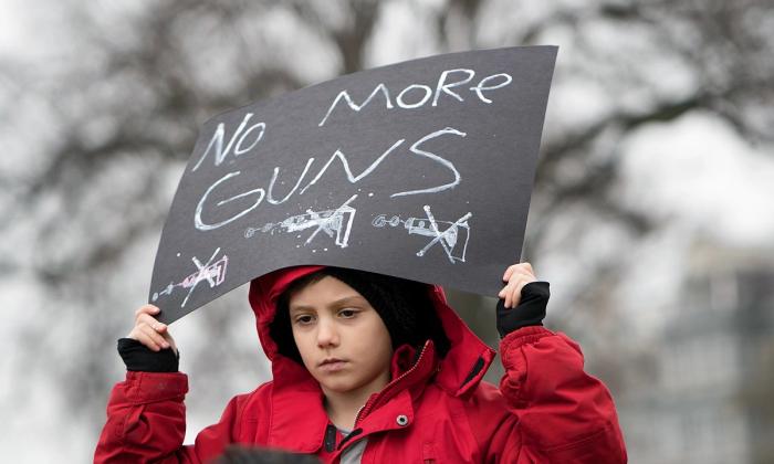 Gutt holder plakat med teksten No more guns. Fra en demonstrasjon i Washington DC i 2018.