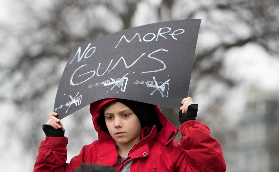 Gutt holder plakat med teksten No more guns. Fra en demonstrasjon i Washington DC i 2018.