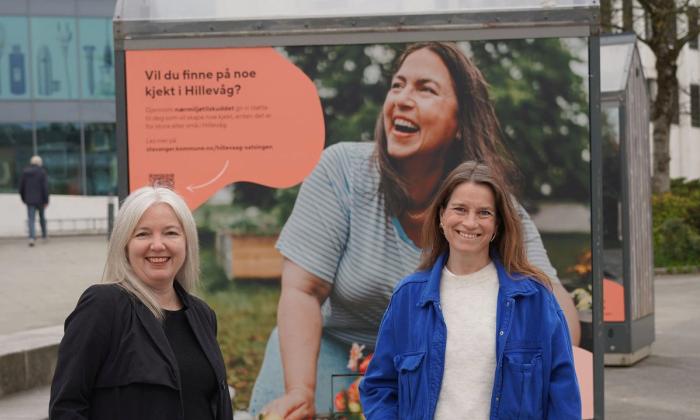 To damer Nina Backhe og Kathrine Idsø, står foran en torvbod utenfor Kilden kjøpesenter og smiler.